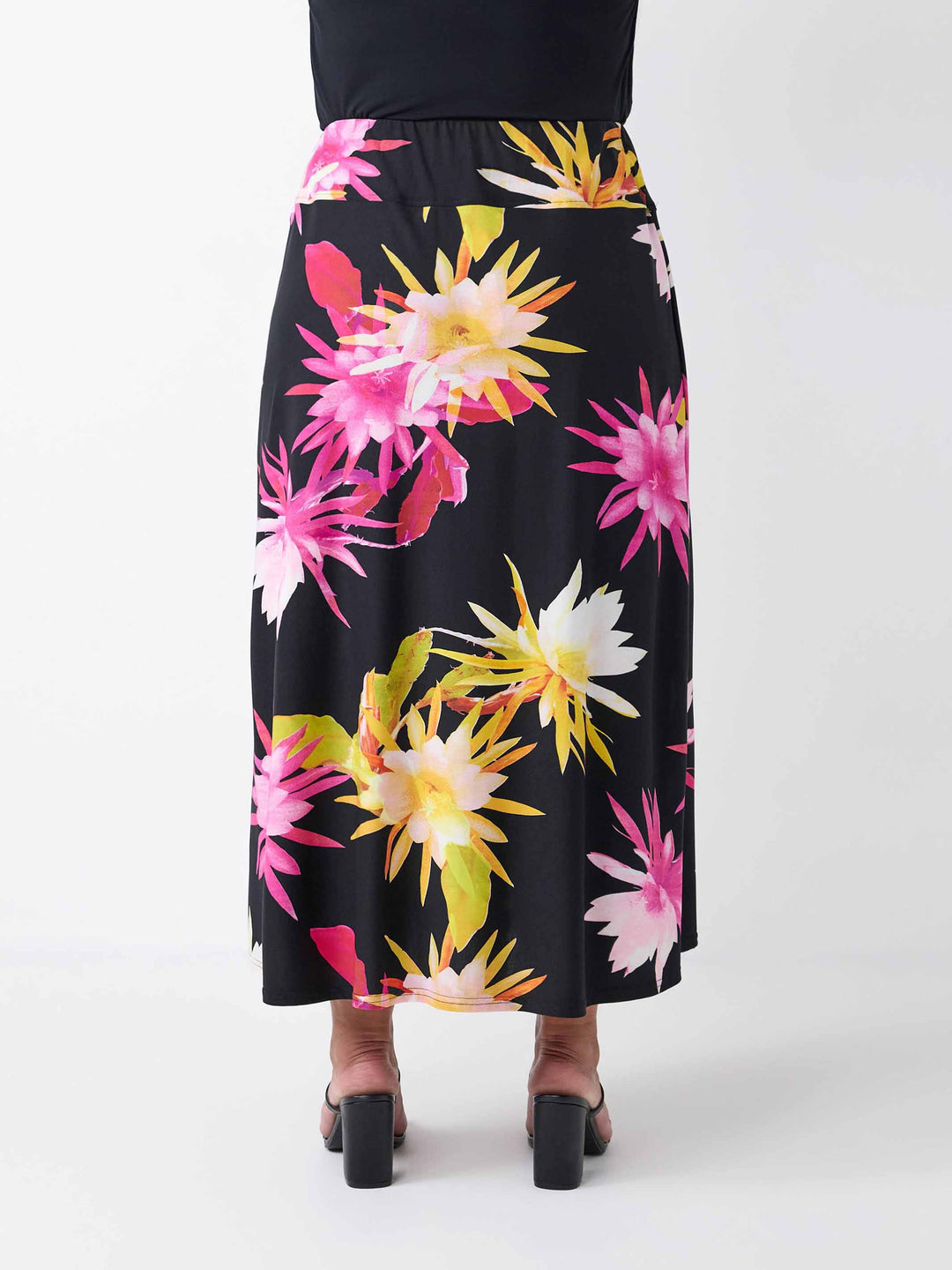 back view of a black midi skirt with a vibrant, large-scale tropical floral print in pink and yellow