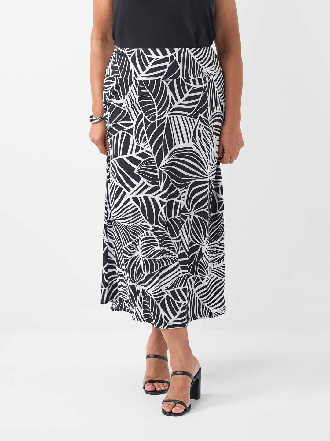front view of a black v-neck top paired with a black and white tropical leaf printed skirt