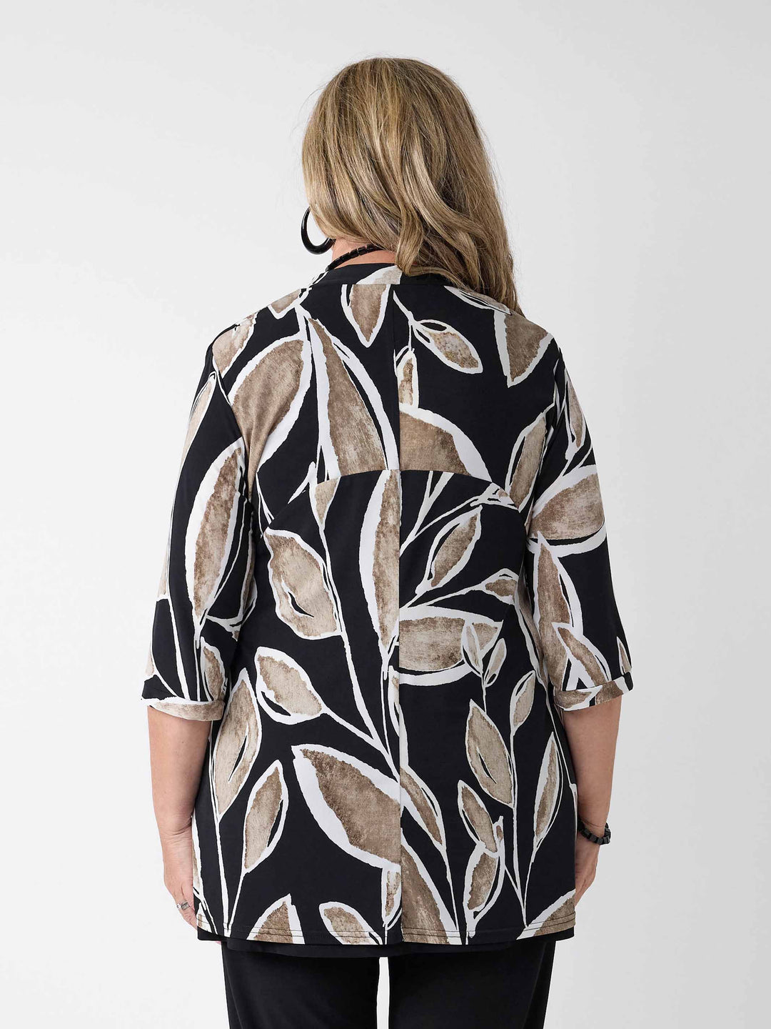 back view of woman wearing a black three-quarter sleeve lightweight jacket with a beige and white leaf pattern