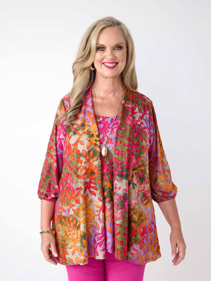 A woman wearing a colourful burnout jacket with three-quarter sleeves in pink over a matching cami and bright pink pants