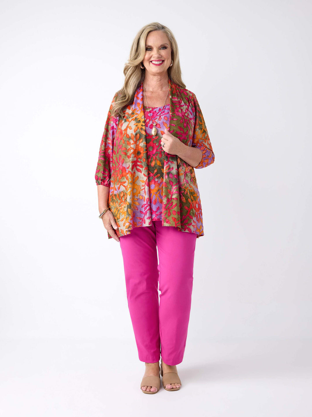 A woman wearing a colourful burnout jacket with three-quarter sleeves in pink over a matching cami and bright pink pants