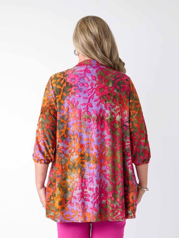 A back view of a woman wearing a colourful burnout jacket with three-quarter sleeves in pink over a matching cami and bright pink pants