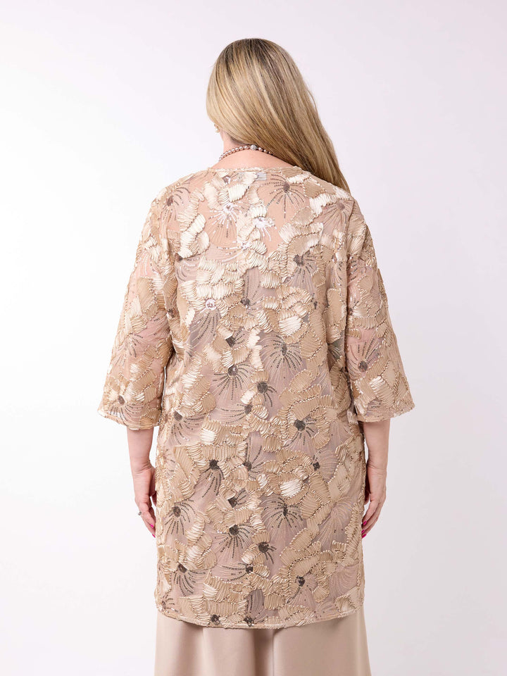 a woman wearing a sheer longline evening jacket which sequin embroidered detail styled with a champagne dress