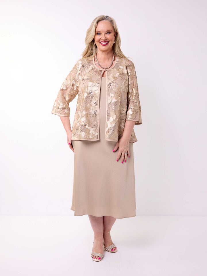 A woman wearing a champagne gold floral embroidered jacket over a matching champagne evening dress