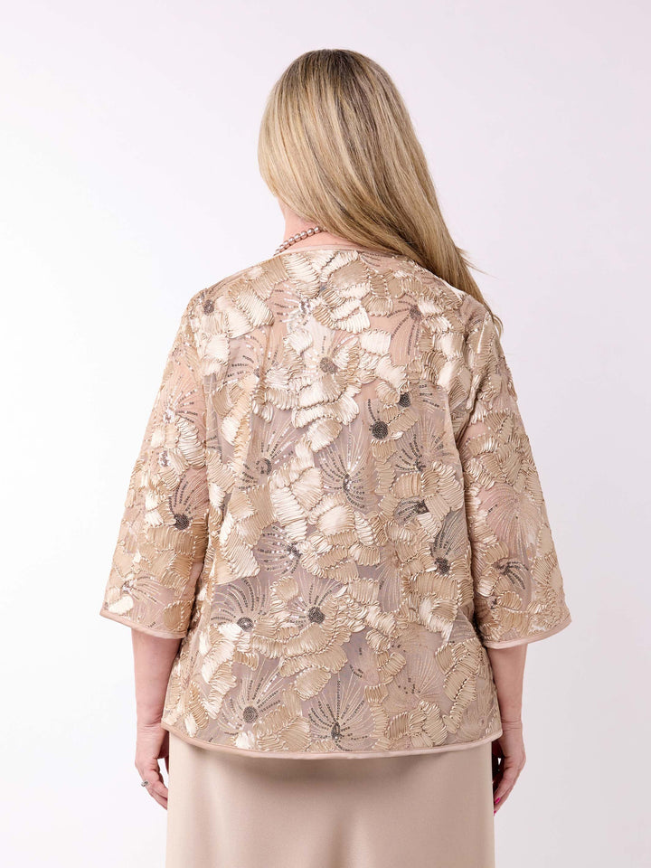 A woman wearing a champagne gold floral embroidered jacket over a matching champagne evening dress
