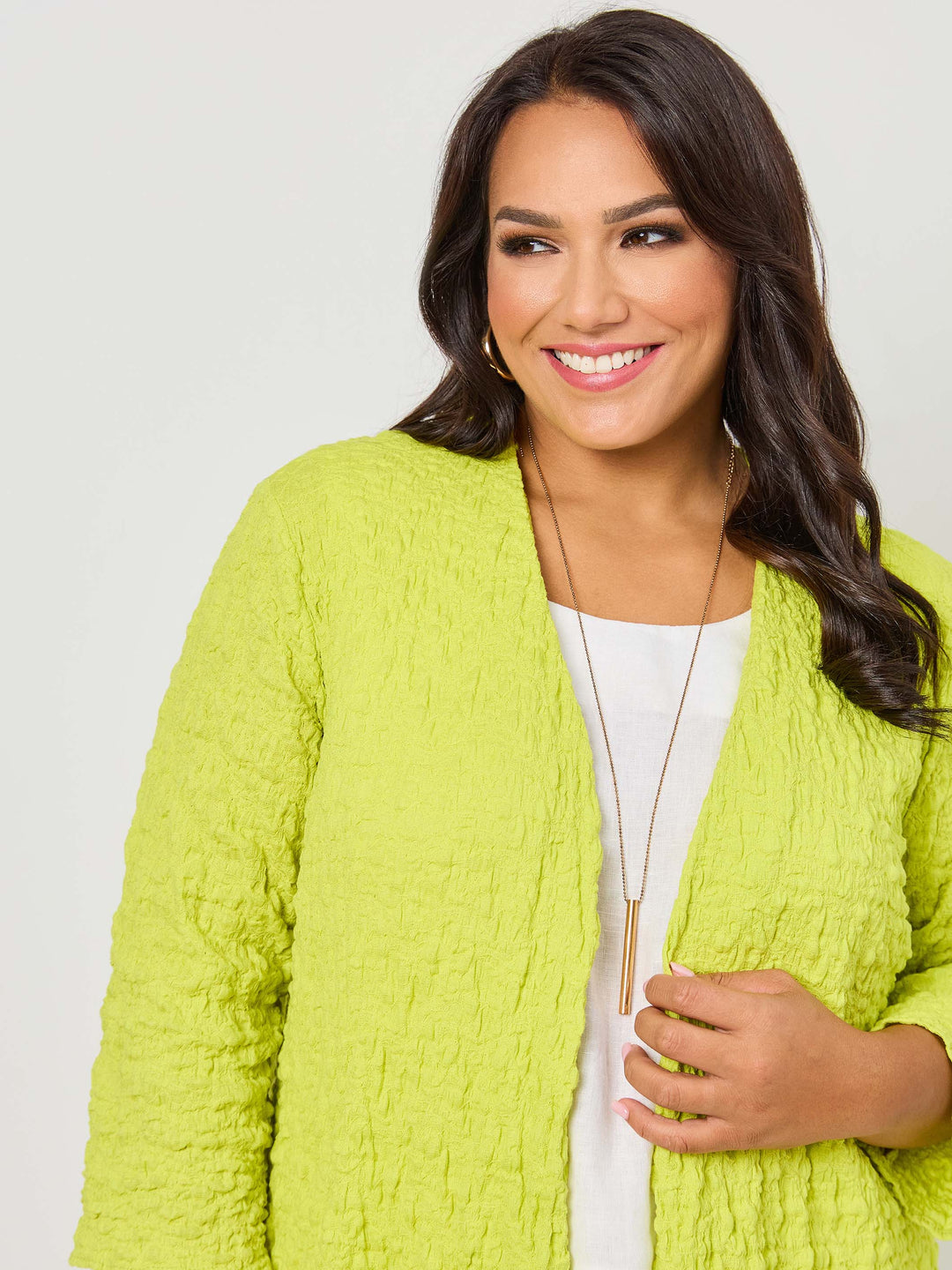 A woman wearing a vibrant fresh lime yellow textured open front cardigan