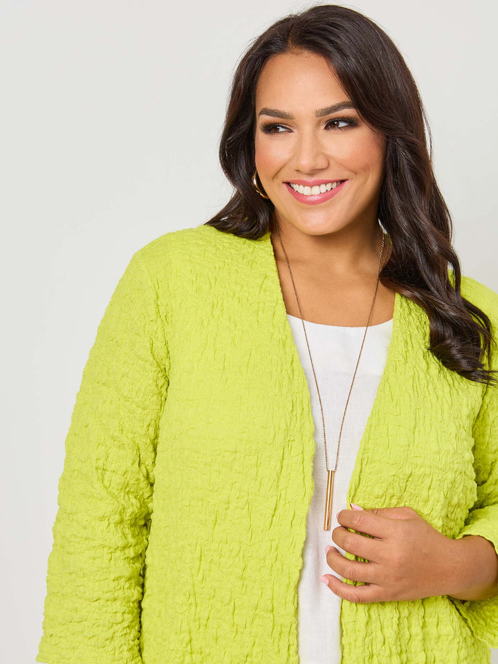 A woman wearing a vibrant fresh lime yellow textured open front cardigan