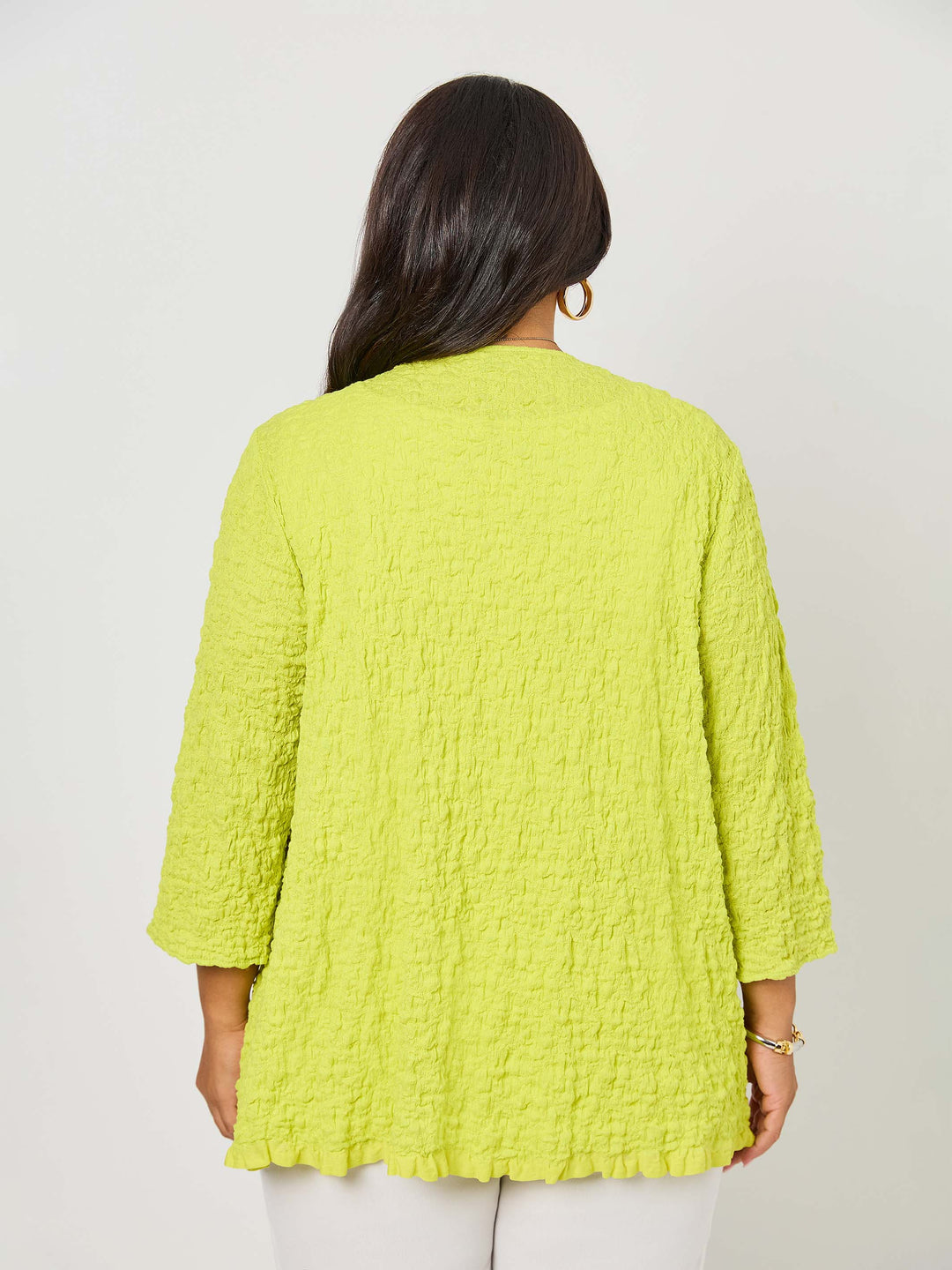 A woman wearing a vibrant fresh lime yellow textured cardigan