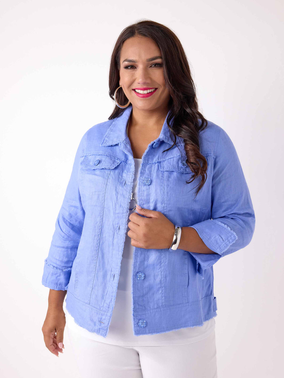 A woman wearing a light blue cropped linen denim style jacket over a white top