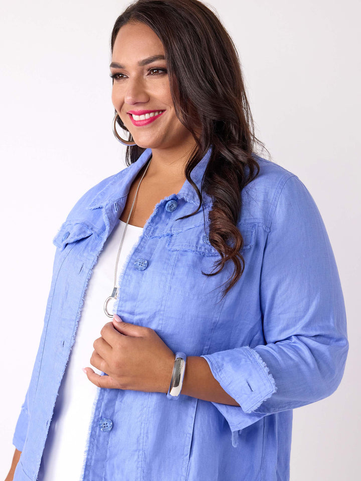 A detailed view of a woman wearing a light blue cropped linen denim style jacket over a white top