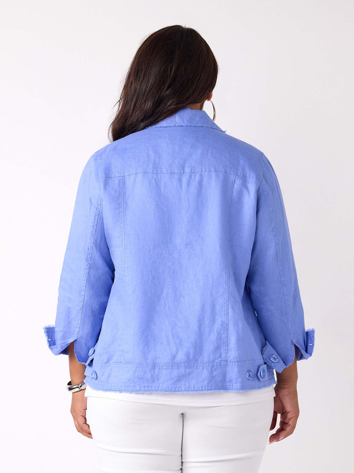 A back view of a woman wearing a light blue cropped linen denim style jacket over a white top