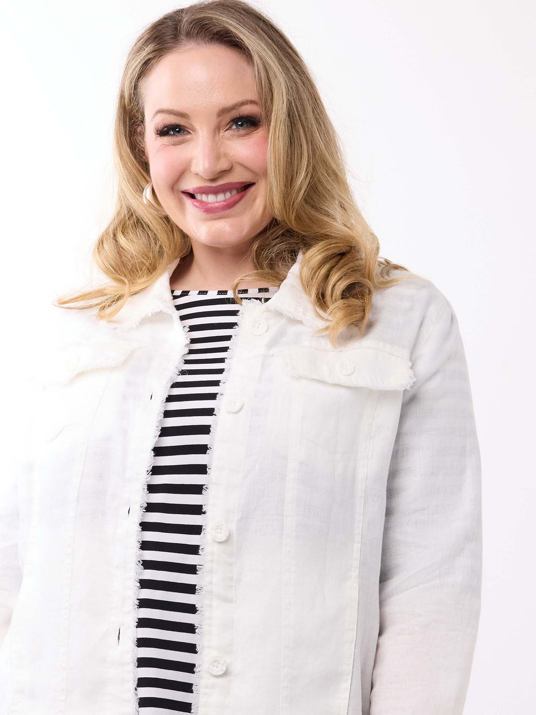 A woman wearing a white lightweight linen jacket over a black and white striped top