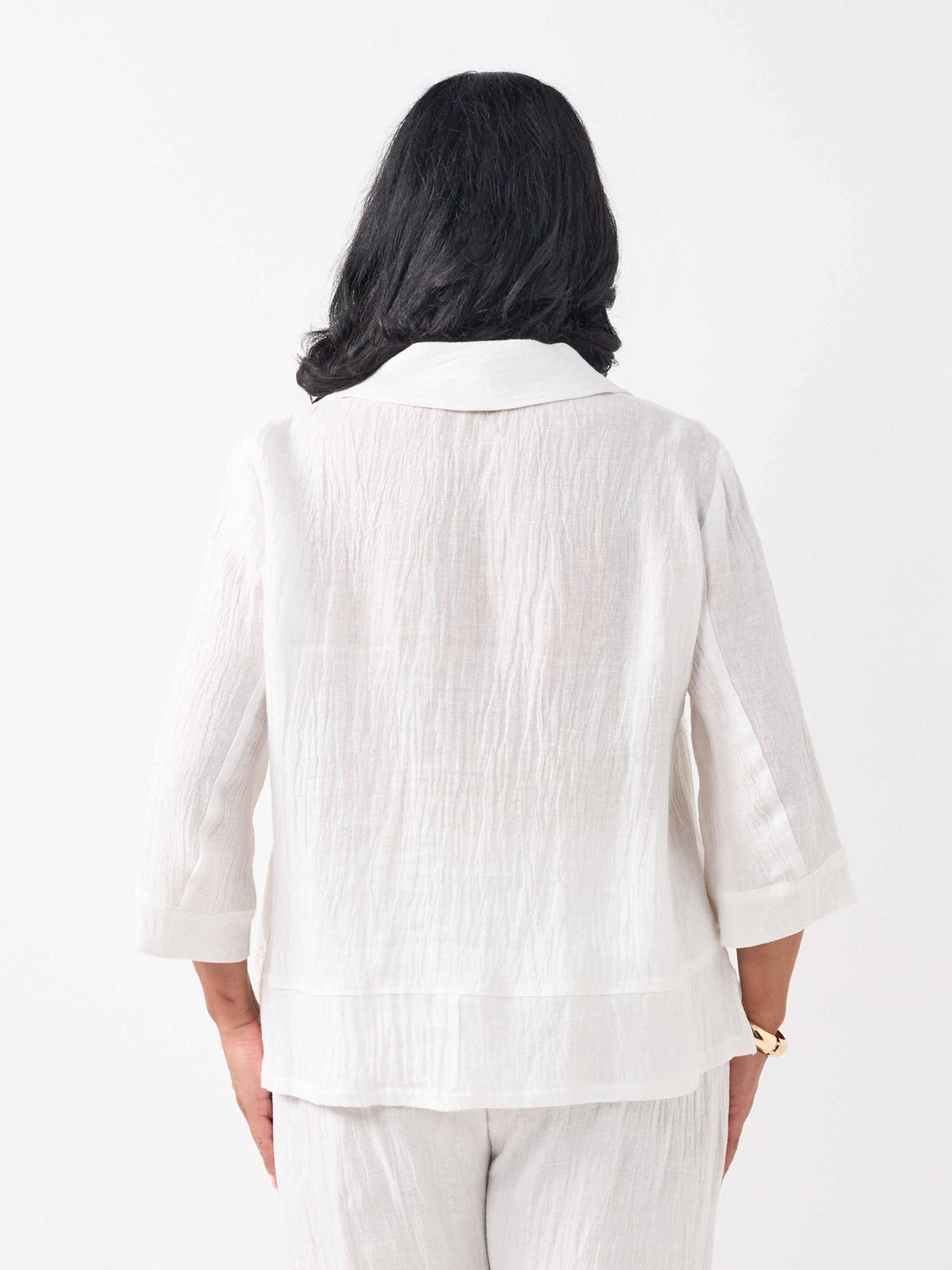 A woman wearing a white textured linen and cotton blend three-quarter sleeve blazer and matching white pants