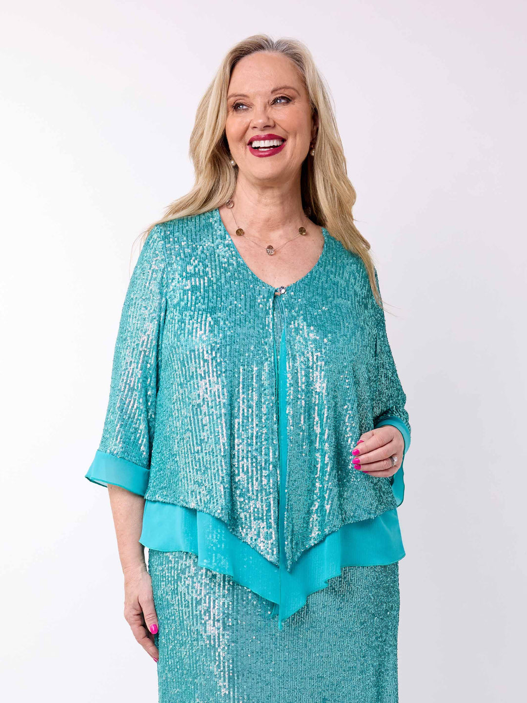 A woman wearing a sparkling teal sequined double-layered evening jacket with a matching dress