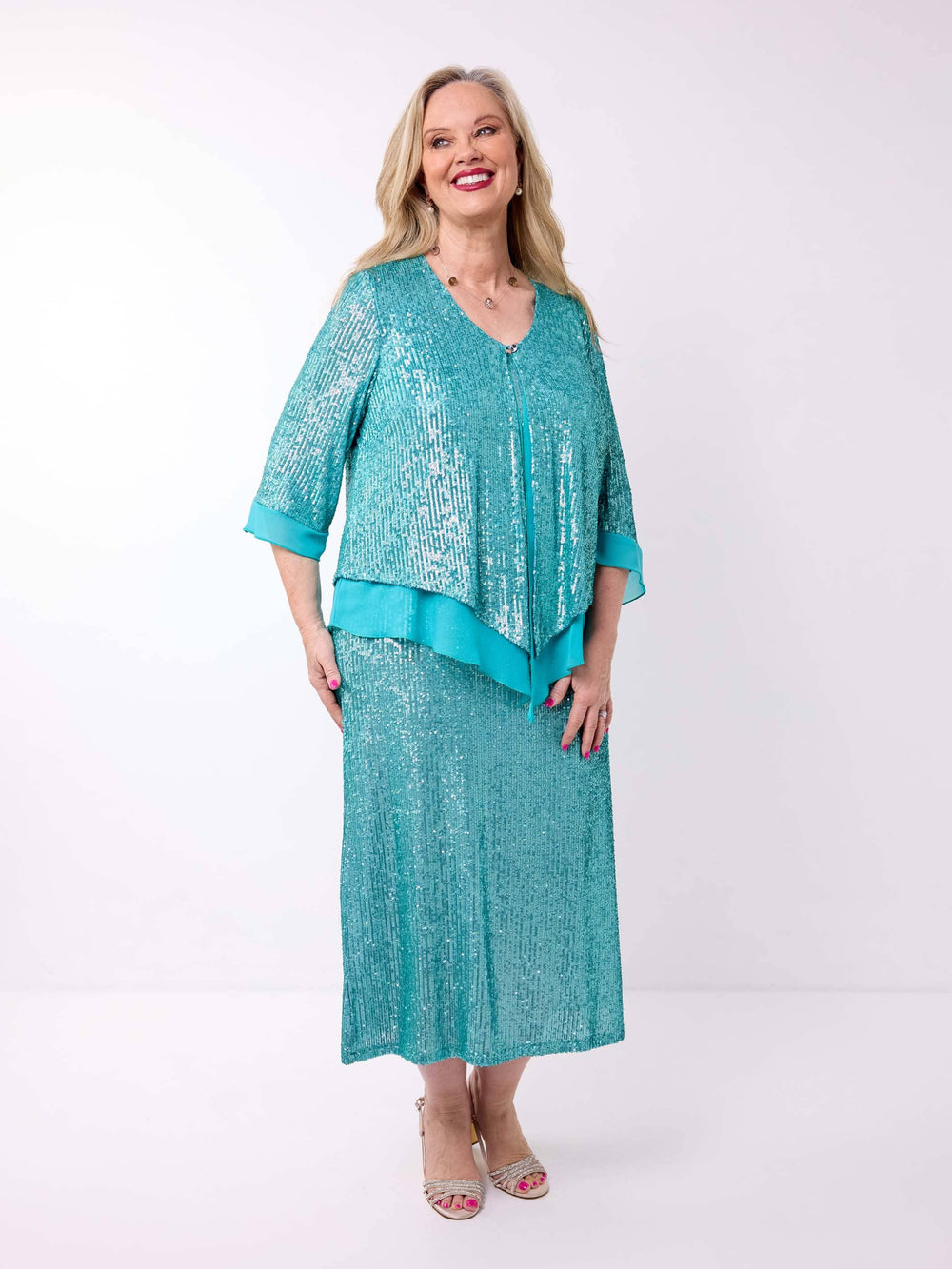 A woman wearing a sparkling teal sequined double-layered evening jacket with a matching dress