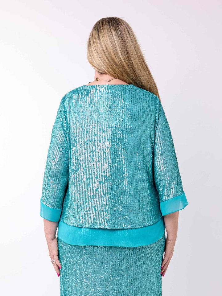 A woman viewed from behind wearing a turquoise sequined jacket with three-quarter sleeves and a matching sequined dress