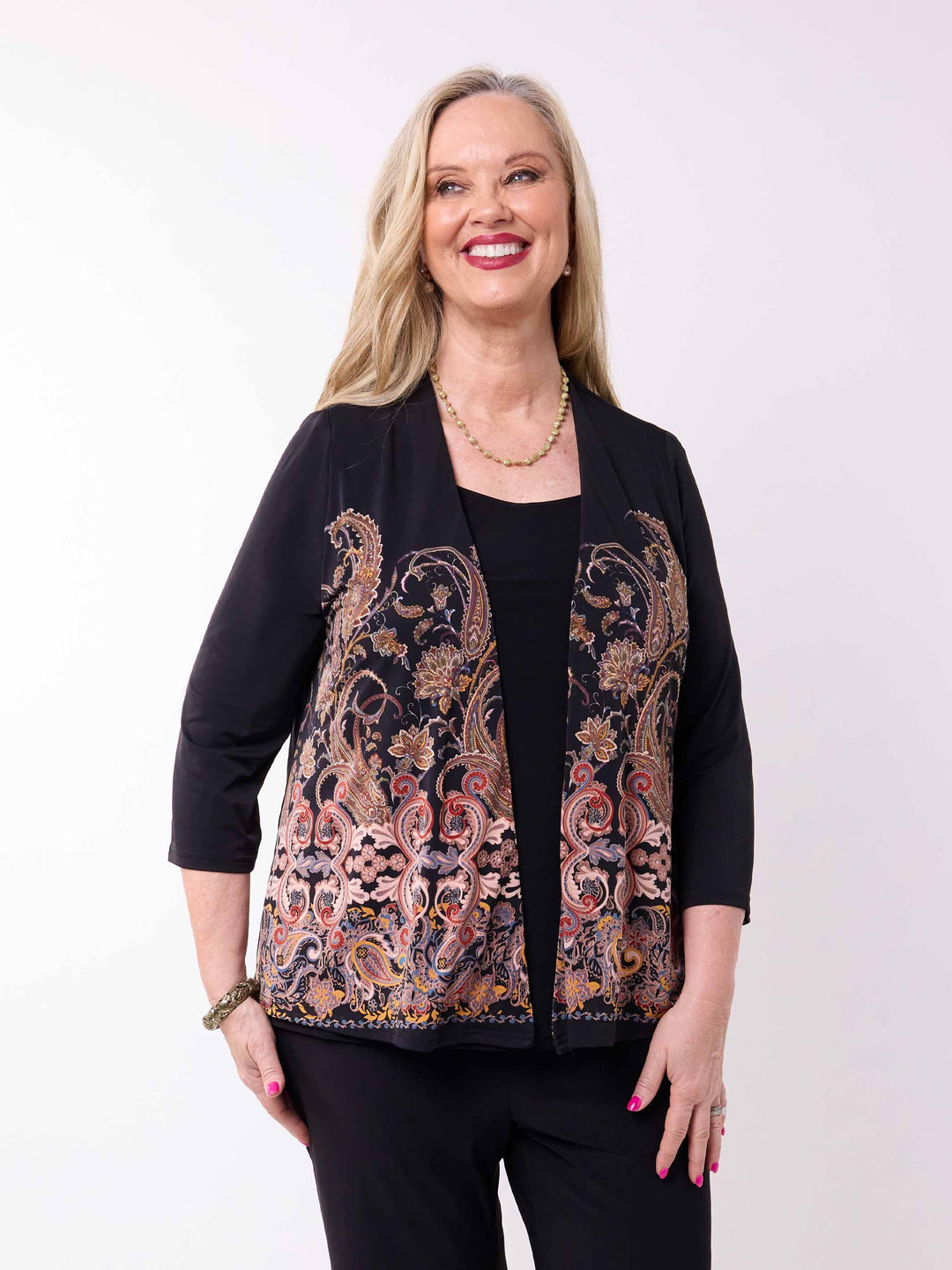 A woman wearing a black three-quarter sleeve short jacket with a large paisley pattern panel in black, gold, and rust