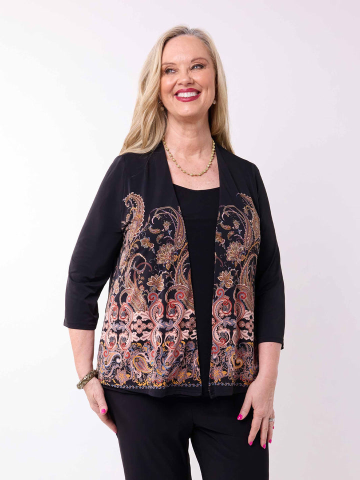A woman wearing a black three-quarter sleeve short jacket with a large paisley pattern panel in black, gold, and rust