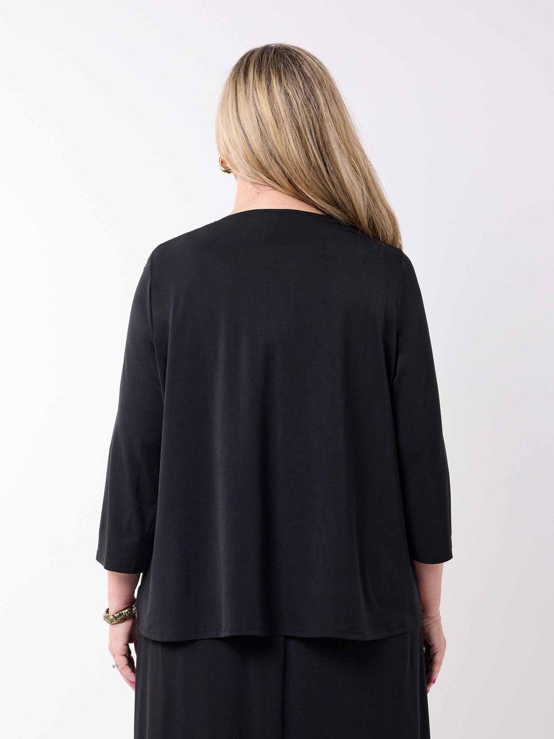 A woman viewed from the back wearing a loose black three-quarter sleeve jacket