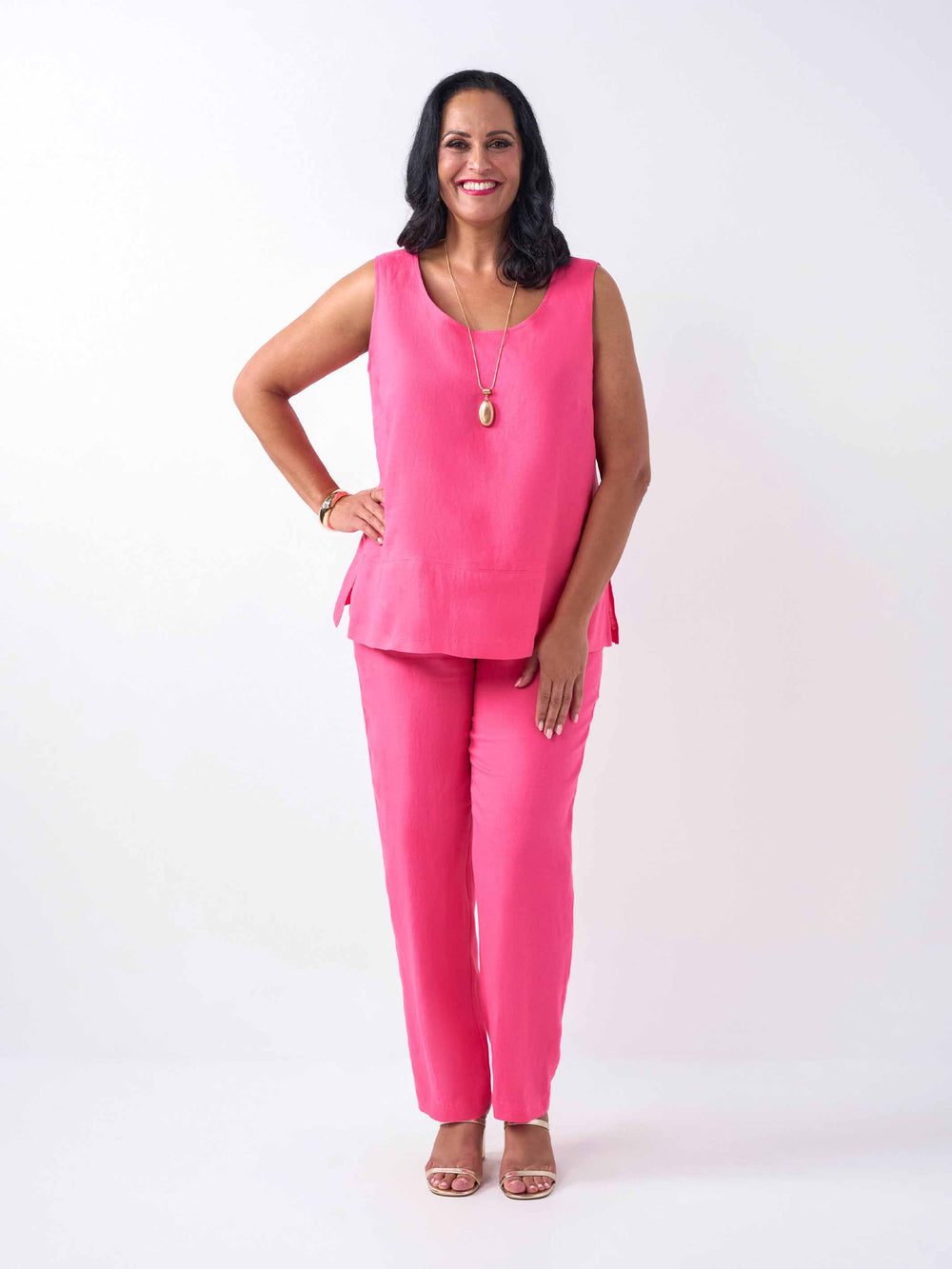 A woman wearing a bright pink sleeveless linen top and matching pink pants