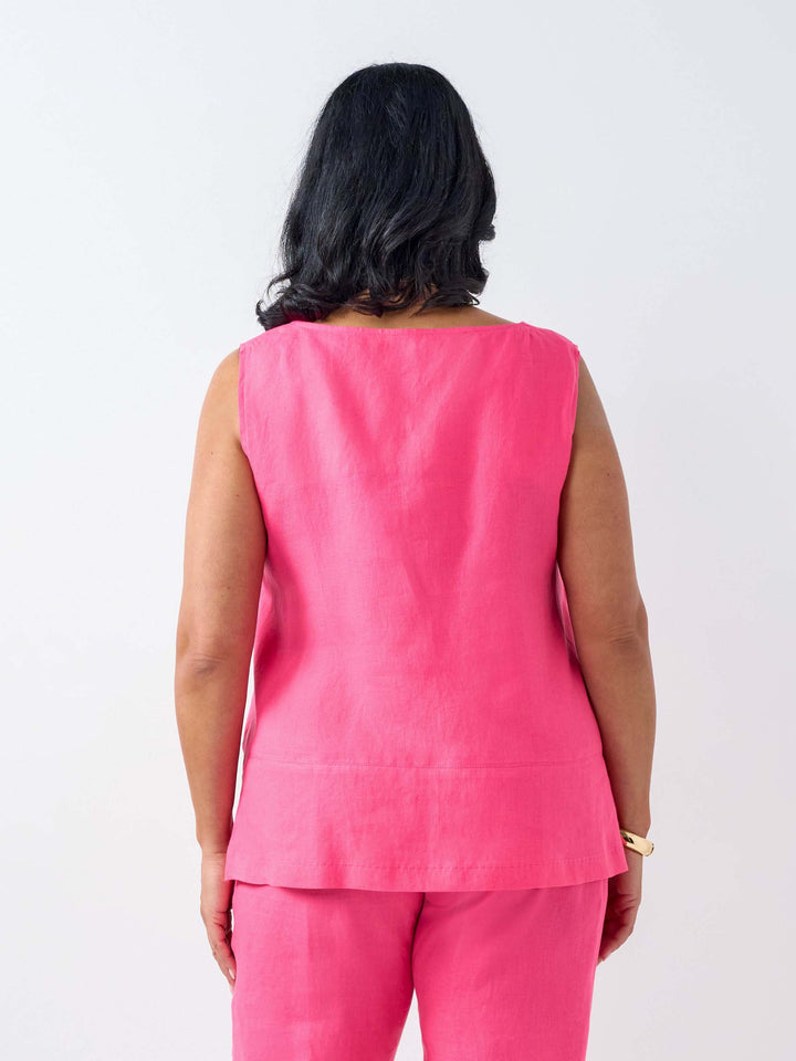 A woman viewed from behind wearing a bright pink sleeveless linen top and matching pink pant