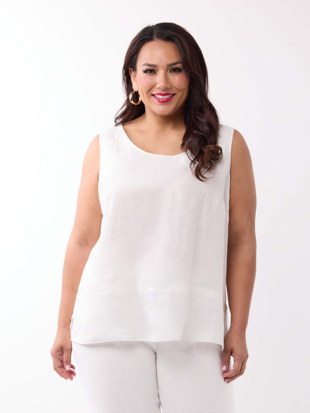 A woman wearing a sleeveless white linen top and white pants