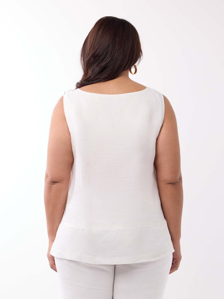 A woman viewed from the back wearing a sleeveless white linen top and white pants