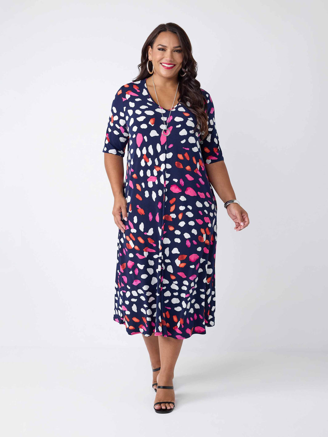 model wearing a navy blue v-neck midi dress with a colourful pebble print of white and pink