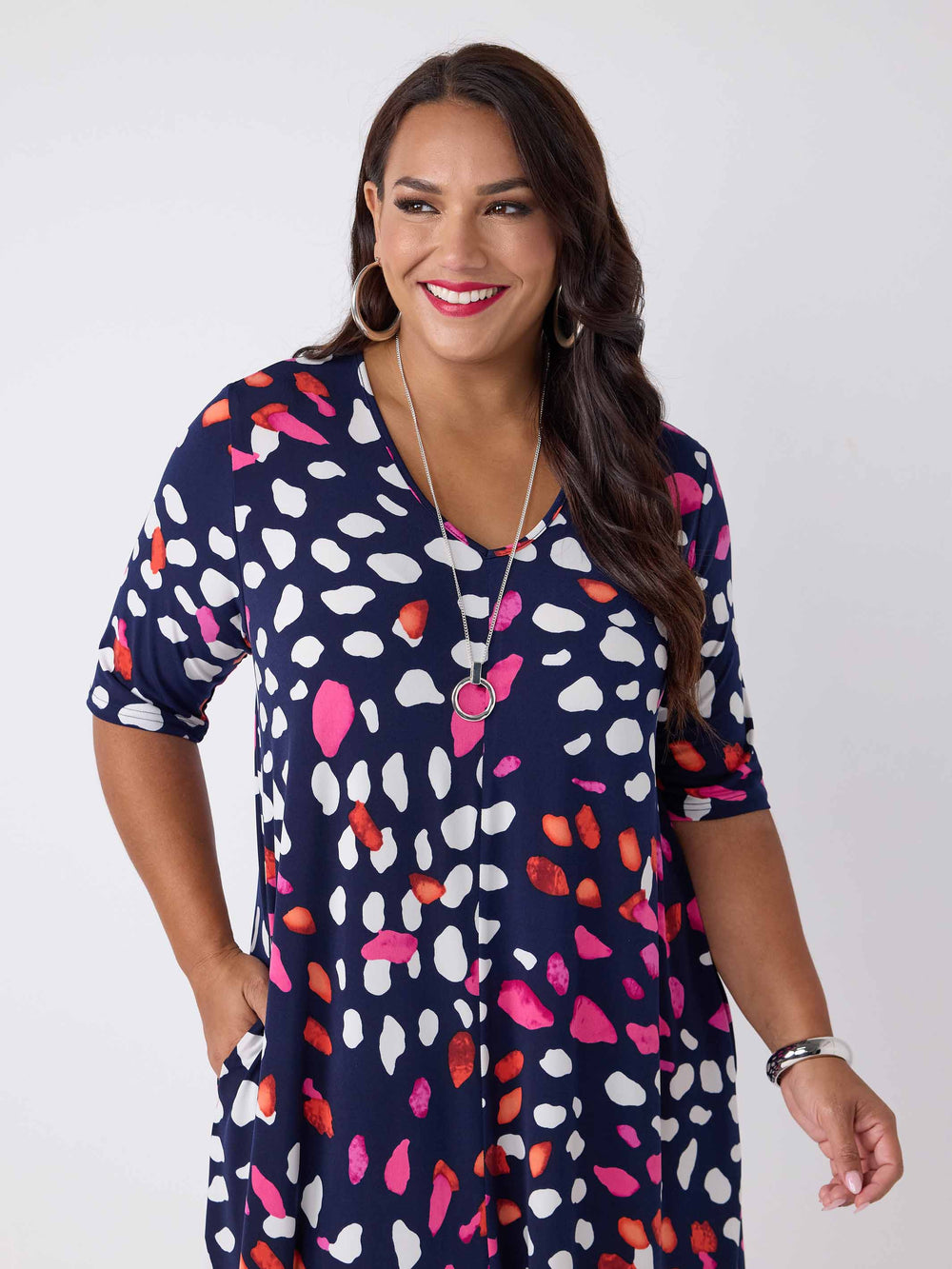 close-up view of model wearing a navy blue v-neck midi dress with a colourful pebble print of white and pink