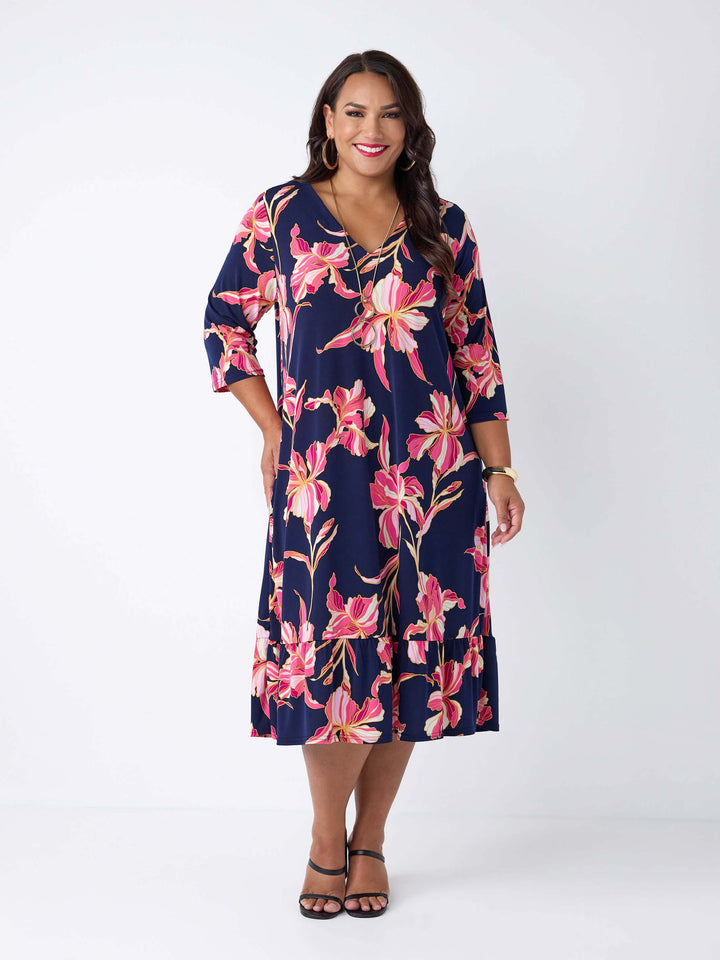 model wearing a navy blue midi dress with a pink floral print, featuring a V-neckline, three-quarter sleeves, and frill hemline