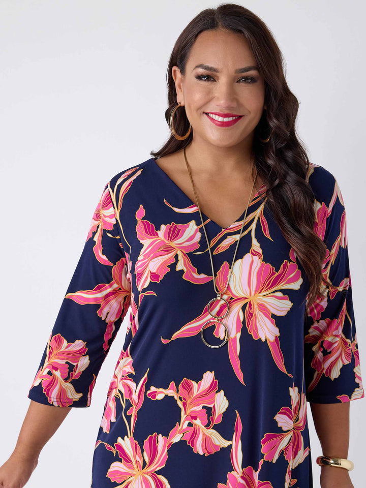 close-up view of model wearing a navy blue midi dress with a pink floral print, featuring a V-neckline, three-quarter sleeves, and frill hemline