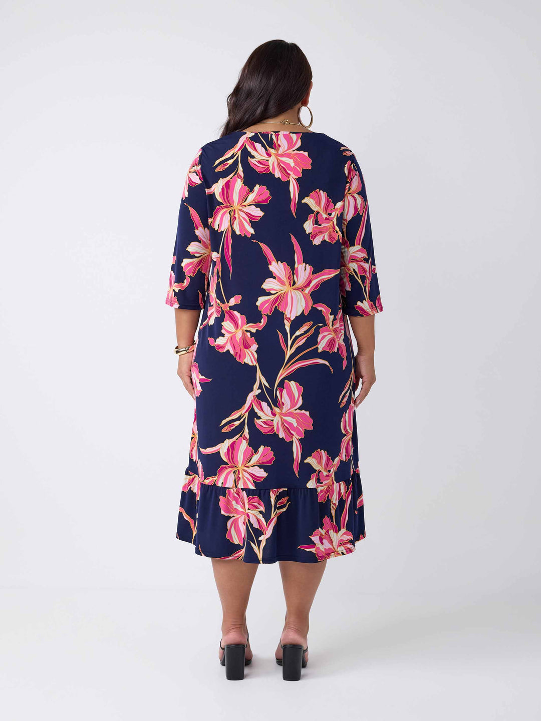 back view of model wearing a navy blue midi dress with a pink floral print, featuring a V-neckline, three-quarter sleeves, and frill hemline