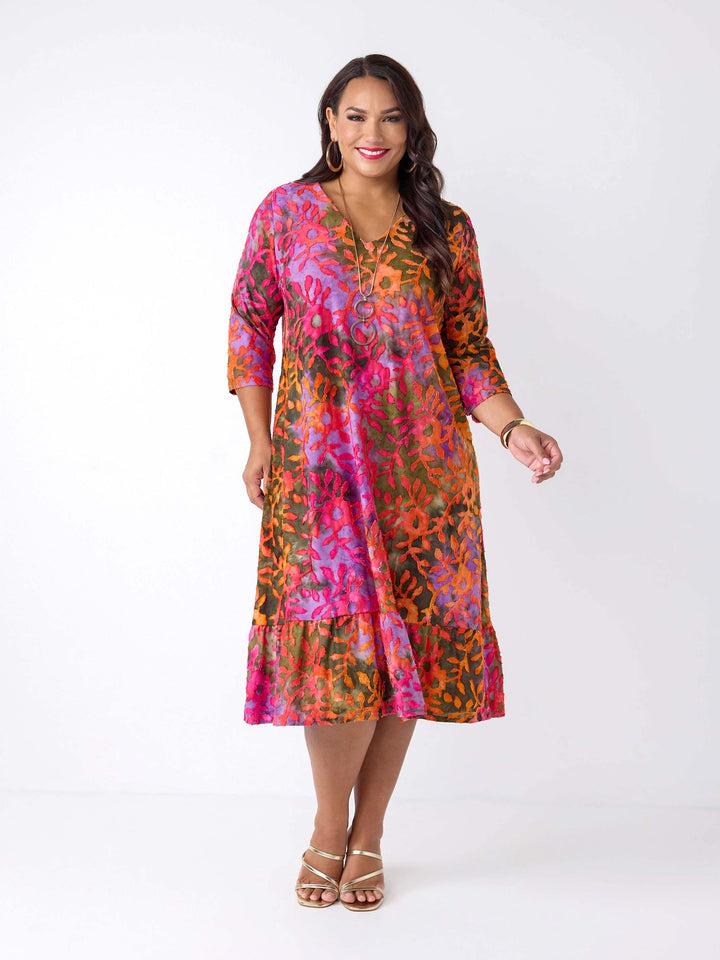 A woman wearing a vibrant, multicoloured burnout floral print midi dress with three-quarter sleeves and a ruffled hem