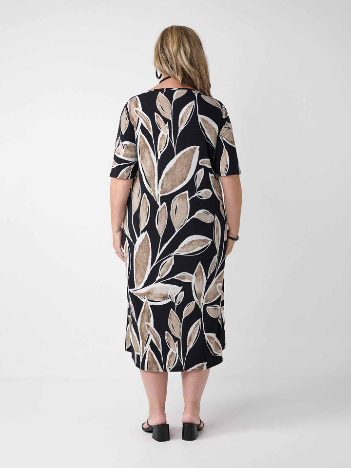 back view of model wearing a short-sleeve midi dress with a black background and a beige leaf pattern