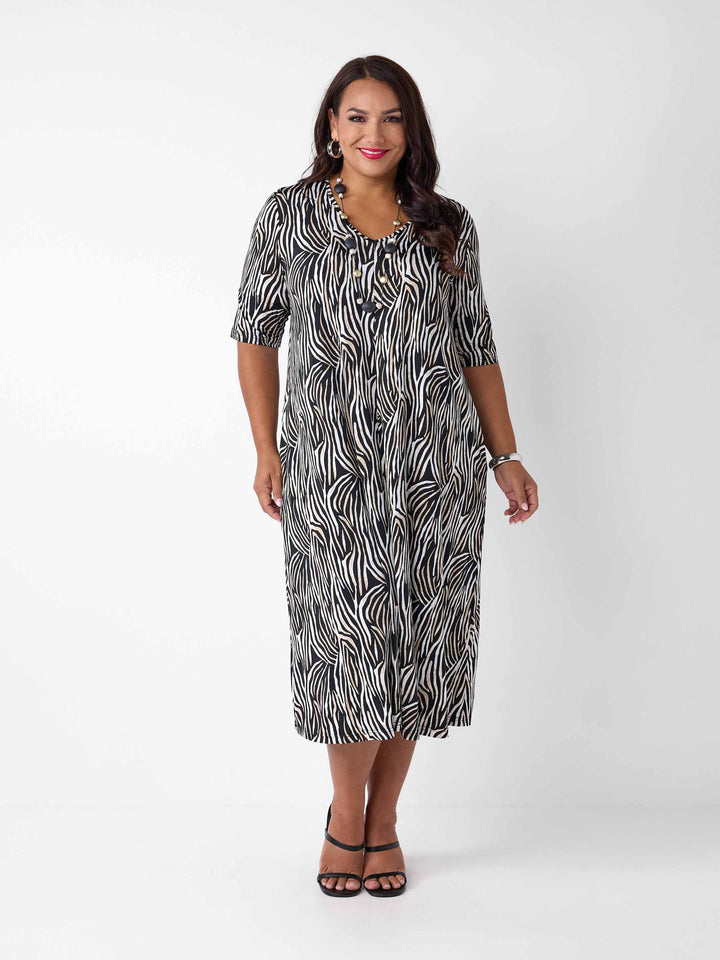 model wearing a black, white, and brown zebra-print midi dress with three-quarter sleeves