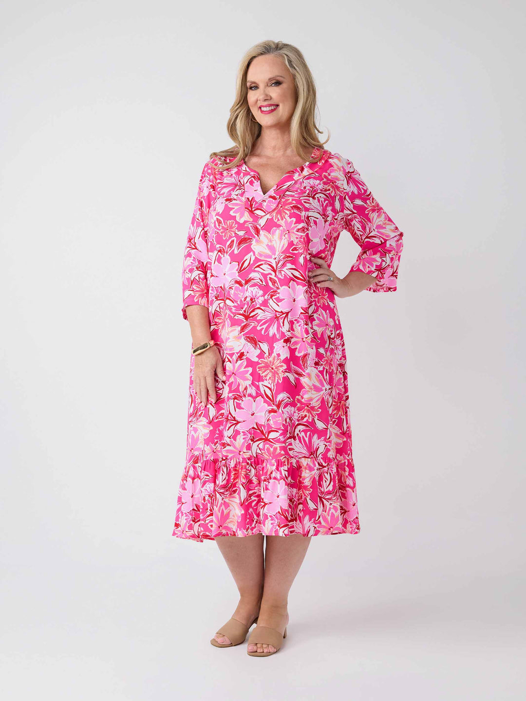 A woman wearing a pink floral midi dress with three-quarter sleeves and a V-inset neckline
