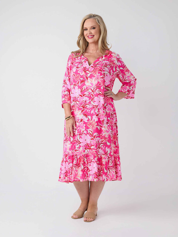 A woman wearing a pink floral midi dress with three-quarter sleeves and a V-inset neckline