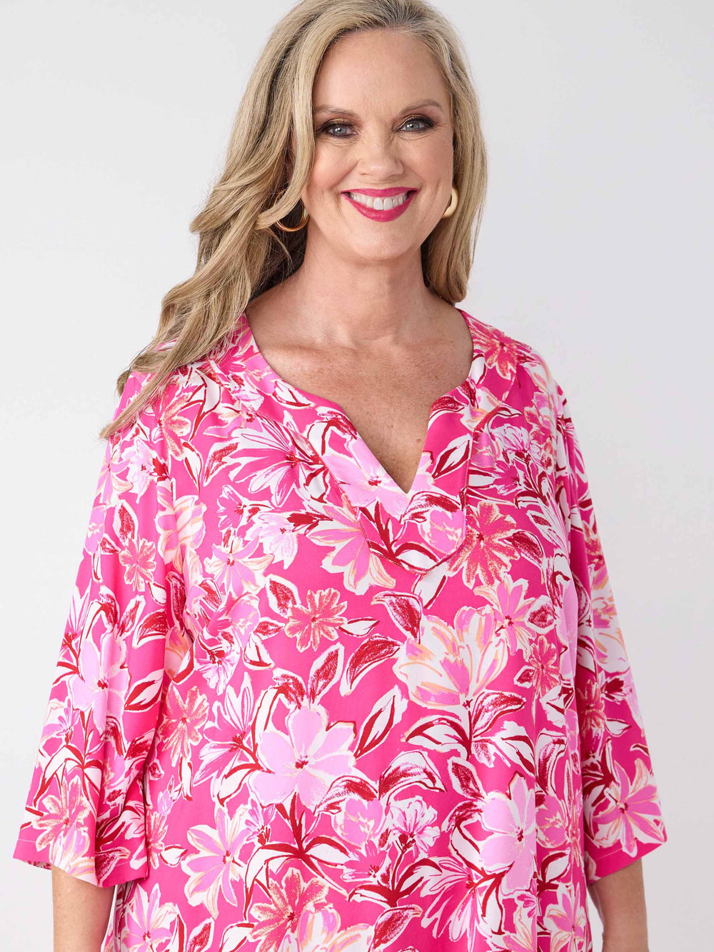 A woman wearing a pink floral midi dress with three-quarter sleeves and a V-inset neckline