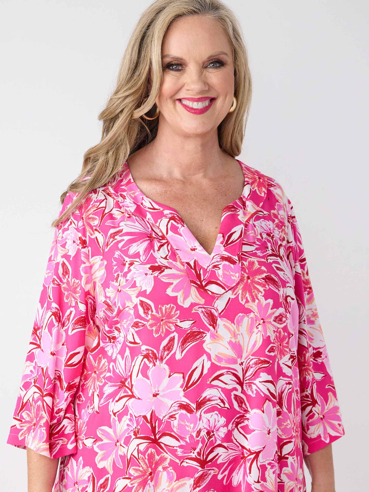 A woman wearing a pink floral midi dress with three-quarter sleeves and a V-inset neckline