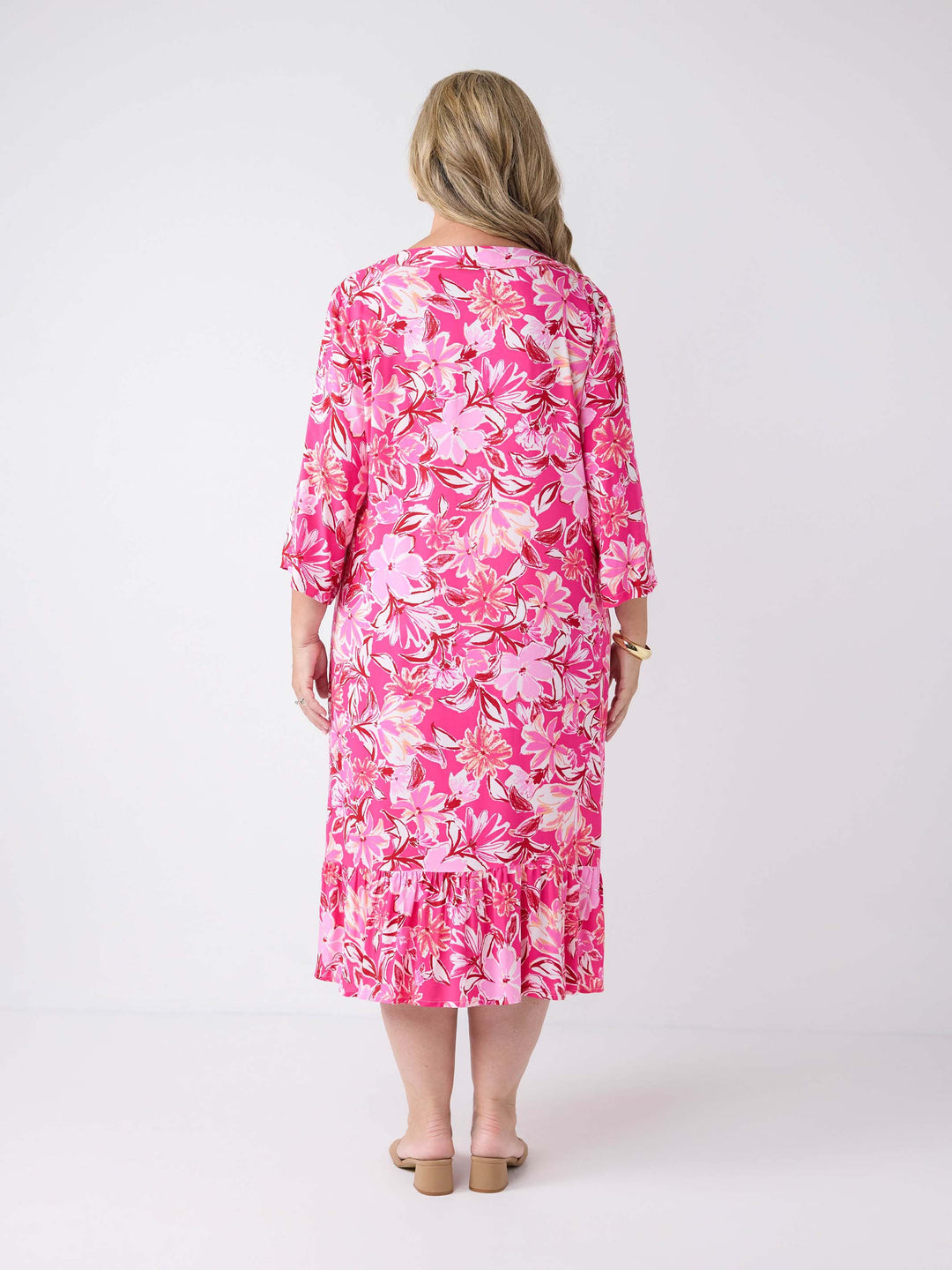 A woman wearing a pink floral midi dress with three-quarter sleeves and a V-inset neckline