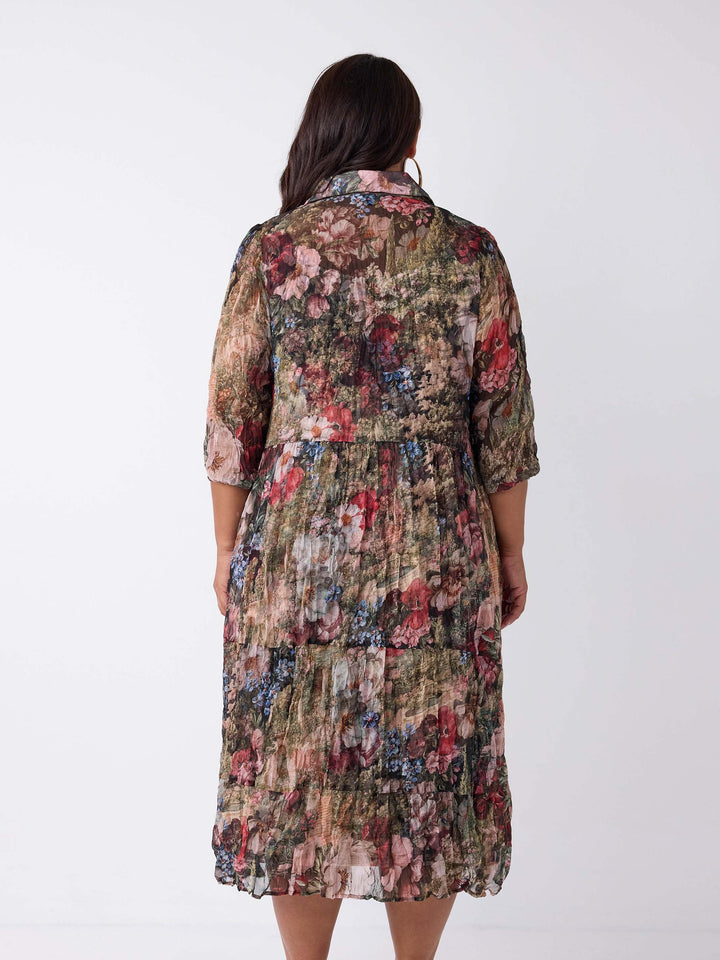 A woman viewed from the back wearing a collared crushed georgette midi shirt dress with garden floral print. 