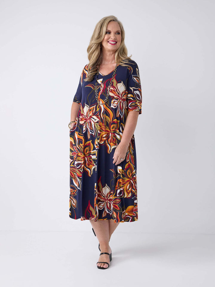 model wearing a short-sleeve midi dress with a navy blue base and a vibrant orange, red, and white floral print