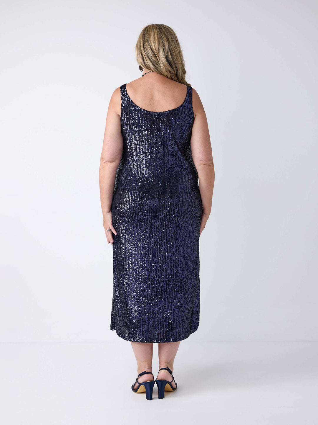 A woman wearing a sleeveless, midi-length navy blue sequined dress