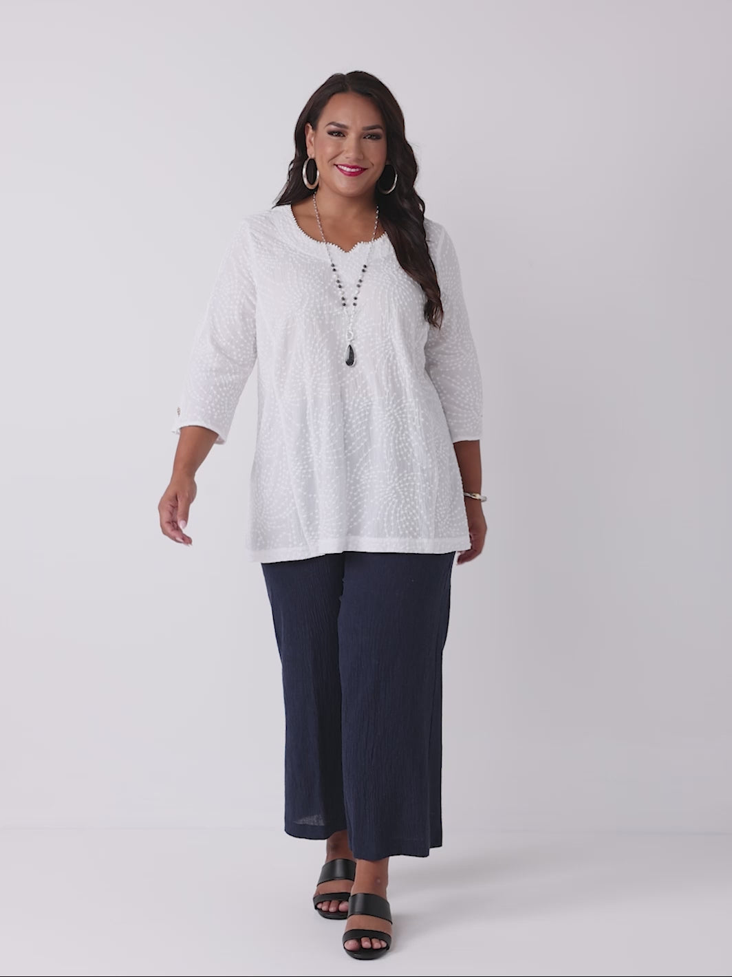 video of model wearing a white three-quarter sleeves top with a textured, dotted pattern