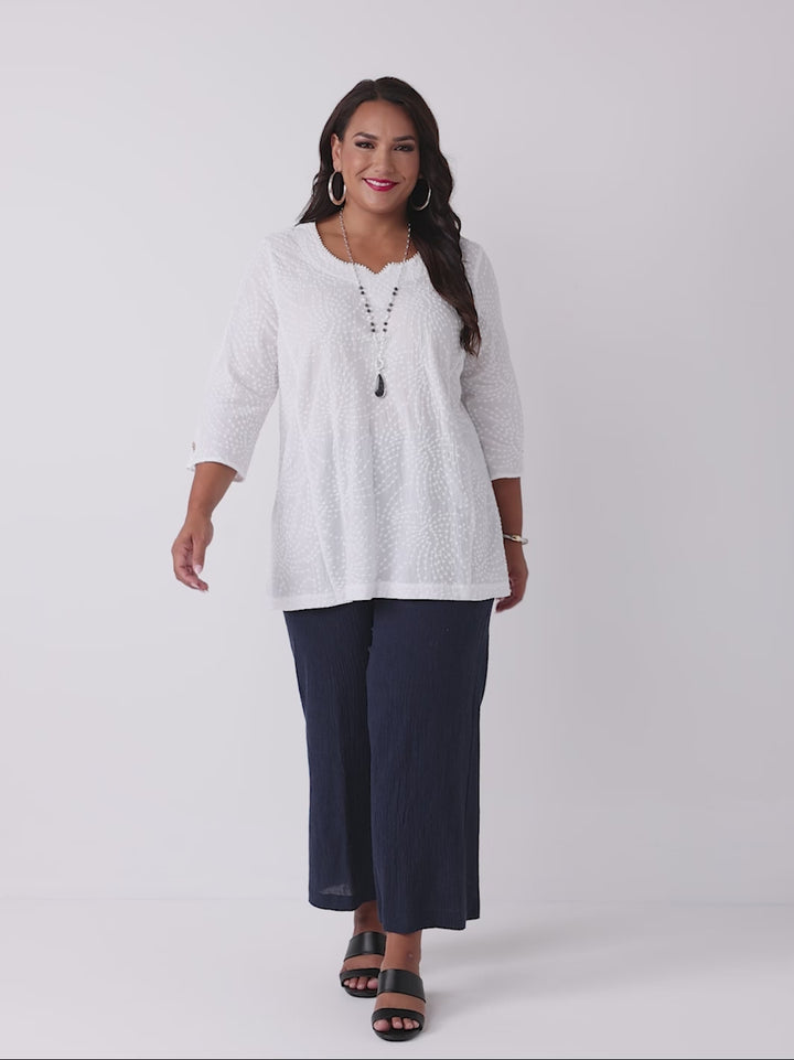 video of model wearing a white three-quarter sleeves top with a textured, dotted pattern