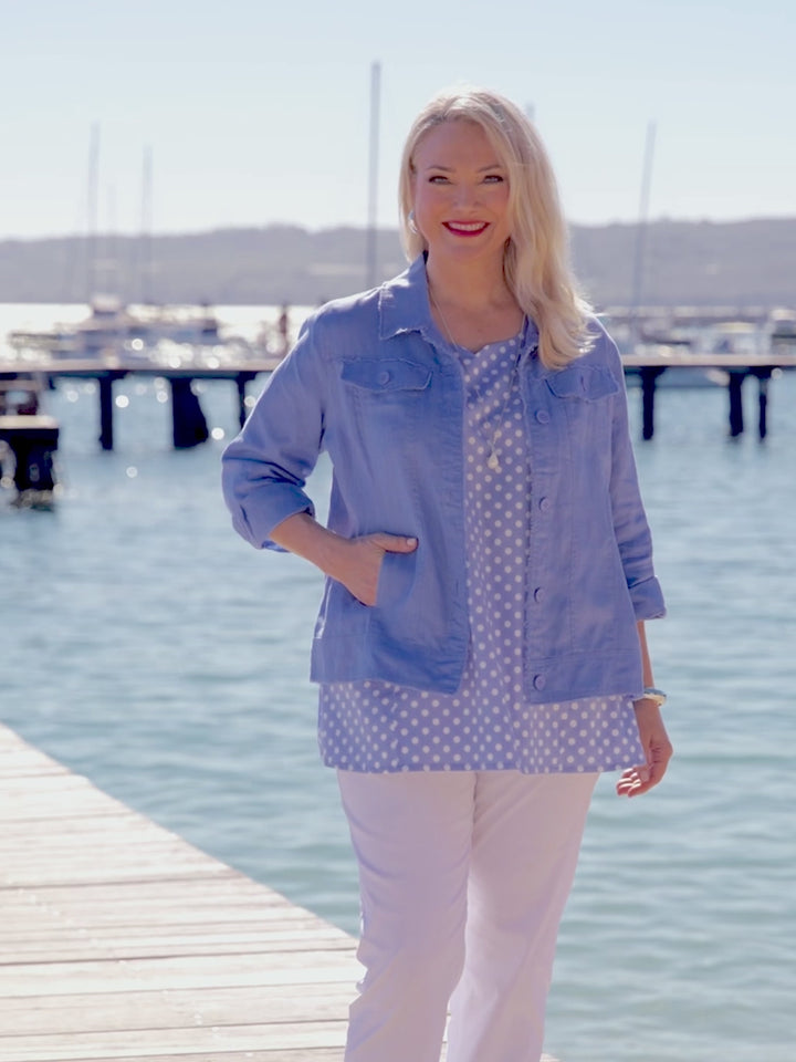 A video of a woman wearing a light blue cropped linen denim style jacket