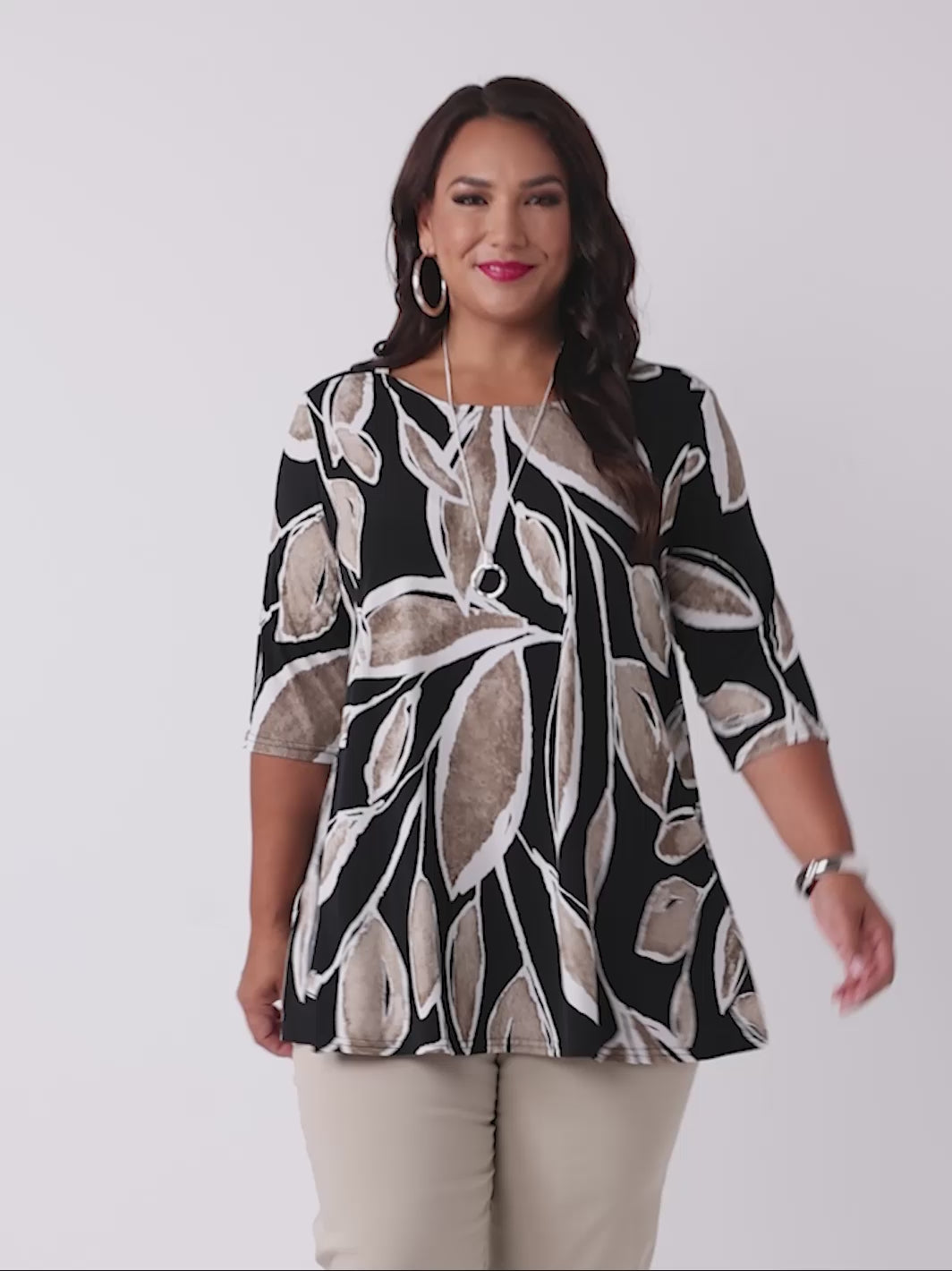 video of model wearing a three-quarter sleeve tunic top with a beige and white leaf print on black base