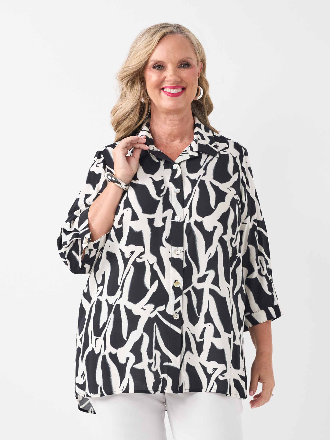 video of model wearing a black and white abstract printed button-up shirt with three-quarter sleeves and white pants
