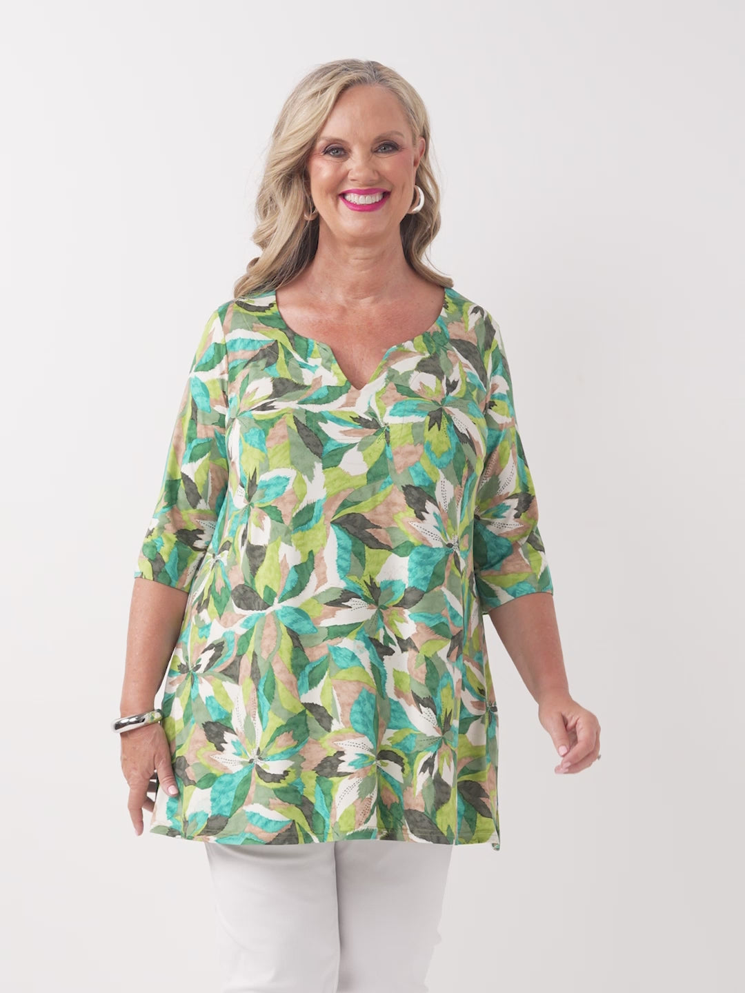 A video of a woman wearing a green tropical floral print tunic top with three-quarter sleeves
