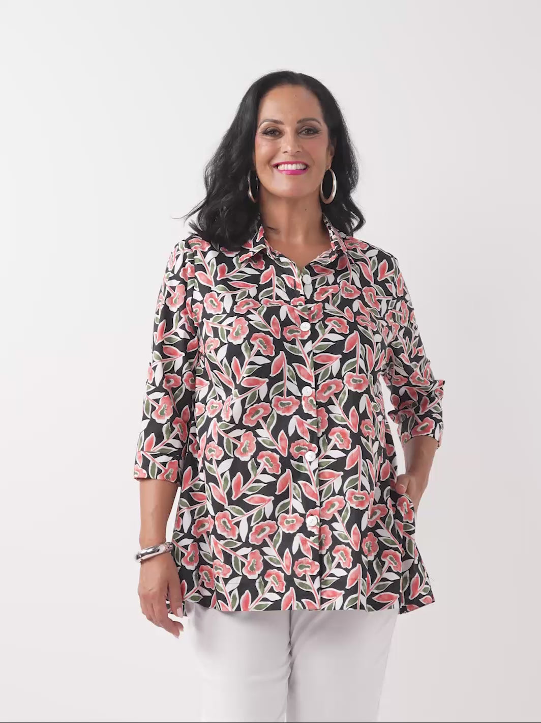 video of model wearing a button-up collared cotton shirt with a red and green floral print